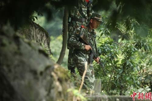 　圖為武警官兵提著槍支搜尋犯罪嫌疑人蹤跡。